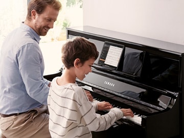 man and young kid playing clavinova piano